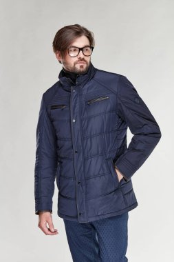 Sakal ve gözlük karanlık sıcak ceket ve koyu mavi pantolon Işık Studio poz ile çekici genç seksi erkek modeli 