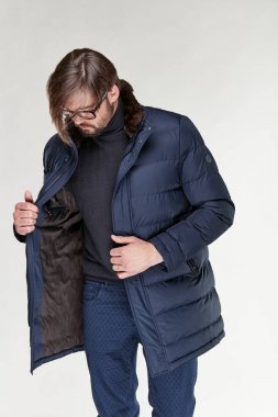 Sakal ve gözlük karanlık sıcak ceket ve koyu mavi pantolon Işık Studio poz ile çekici genç seksi erkek modeli 