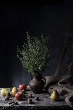 Ceviz, armut, elma ve sürahi ile yeşil bitkilerde, karanlık Studio ahşap masa üzerinde büyük natürmort