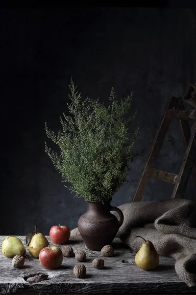 Muhteşem natürmort ceviz, armut, elma ve sürahi ile karanlık Studio ahşap masa üzerinde yeşil bitkiler