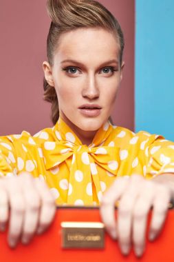 Beyaz benekli, mavi etek ve pembe tayt pin-up tarzı, Studio mavi ve pembe arka plan kırmızı el çantası ile poz ile portre çekici genç seksi gülümseyen kadın model giyen sarı bluz