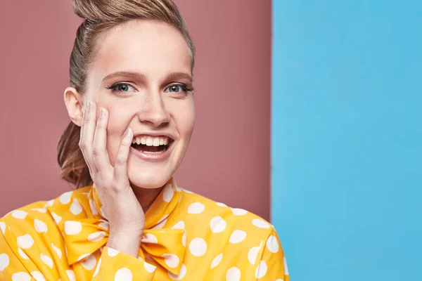 Retrato de primer plano de una joven bonita modelo sonriente sexy con blusa amarilla con lunares blancos, posando en un estudio con fondo azul y rosa —  Fotos de Stock