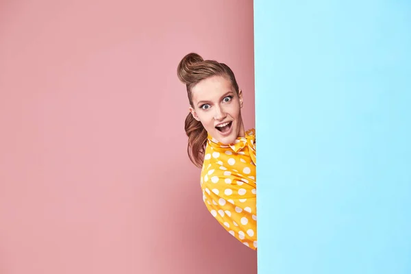 Πορτρέτο του όμορφη νεαρή γυναίκα μοντέλο φοράει κίτρινο μπλούζα με λευκό πουά, μπλε φούστα σε στυλ pin-up, θέτοντας και ψάχνει έκπληξη στο studio με μπλε και ροζ φόντο — Φωτογραφία Αρχείου
