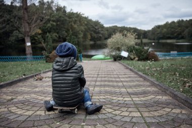 Gri paten kurulu Park sürme koyu gri ceket, koyu mavi kap ve mavi jeans, şirin küçük cesur çocuk