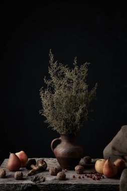 Elma, armut, ceviz, mantar, kızılcık ve sürahi bir yana, karanlık Studio'da çuval bezi ile ahşap yüzey üzerinde bitki ile güzel natürmort 