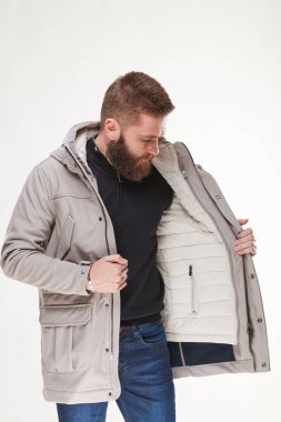 Çekici genç seksi erkek modeli siyah kazak, bej gri ceket ve koyu mavi pantolon Işık Studio poz sakallı 