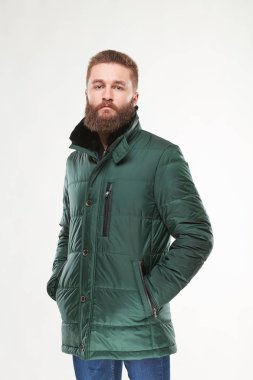 Çekici genç erkek model yeşil bir ceket ve koyu mavi pantolon Işık Studio poz sakallı 