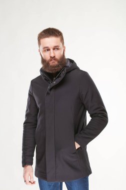 Çekici genç seksi erkek modeli sakallı karanlık kış ceket ve koyu mavi pantolon Işık Studio poz 