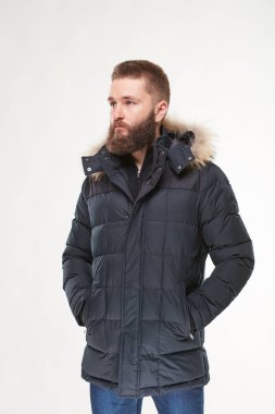 Çekici bir genç adam modeli sakallı karanlık kış ceket ve koyu mavi pantolon Işık Studio poz 
