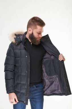 Çekici genç ve seksi erkek modeli sakallı karanlık kış ceket ve koyu mavi jeans Işık Studio poz 