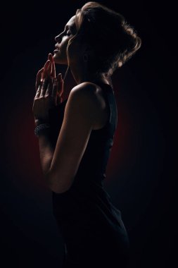 İpeksi siyah elbise ve şık takı, stüdyoda poz giyen muhteşem sarışın seksi kadın ile göz alıcı makyaj, karanlık portresi