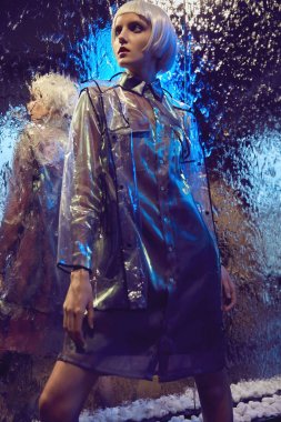 Beyaz bob saç modeli ipeksi bluz ve şeffaf kat ayakta ıslak cam yakınındaki giymiş bir kızla fütüristik neon ışıklı portresi