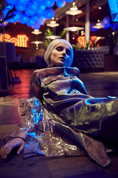 Beyaz bob saç modeli ipeksi bluz ve katta oturan şeffaf yağmurluk giymiş bir kızla fütüristik neon ışıklı portresi