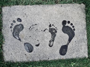 Bir yetişkin ve bir çocuk gri bir yüzey üzerinde ayak izleri