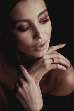 Kahverengi gözleri ve güzel elleri ile şık ve seksi esmer kadın portresi karanlık stüdyo