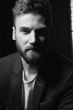 Siyah beyaza yakın koyu saç, sakal ve bıyık koyu ceket giyen genç çekici adam portresi kadar. Stüdyo vurdu 