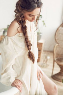 Güzel seksi ve genç kadının karanlık örgü giyen basit ışık ile parlak portre Studio büyük pencereler, bitkiler, banyo ve hasır sandalye ile elbise