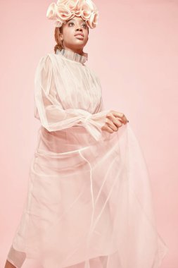 Yumuşak studio toz pembe tül elbise ve büyük fırfır hairband poz güzel siyah kadın portresi. Pembe bir arka plan