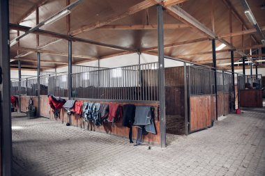 Horse barn with open wooden door. With set of saddle pads    clipart