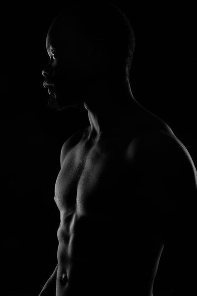 black and white portrait of a handsome black man with naked sports torso on dark background