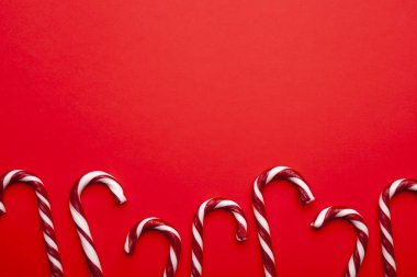 Kırmızı arka planda Noel şekerlerinden yapılmış bir çerçeve. Metin için boşluk olan üst görünüm. En düşük bileşim