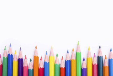 Beyaz arka planda farklı renkli kalemler. Renkli kalemlerle yapılmış çerçeve, yakın plan görünümü, metin için boşluk