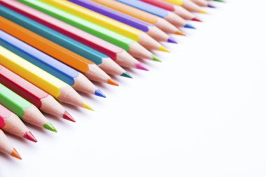 Beyaz arka planda farklı renkli kalemler. Renkli kalemlerle yapılmış çerçeve, yakın plan görünümü, metin için boşluk