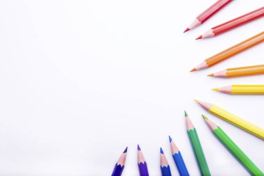 Beyaz arka planda farklı renkli kalemler. Renkli kalemlerle yapılmış çerçeve, yakın plan görünümü, metin için boşluk