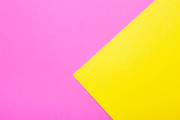 Pink and yellow paper as background. Two colored bright paper texture, top view with place for text