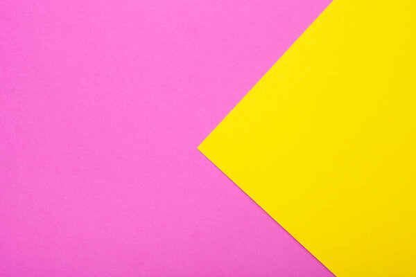 Pink and yellow paper as background. Two colored bright paper texture, top view with place for text