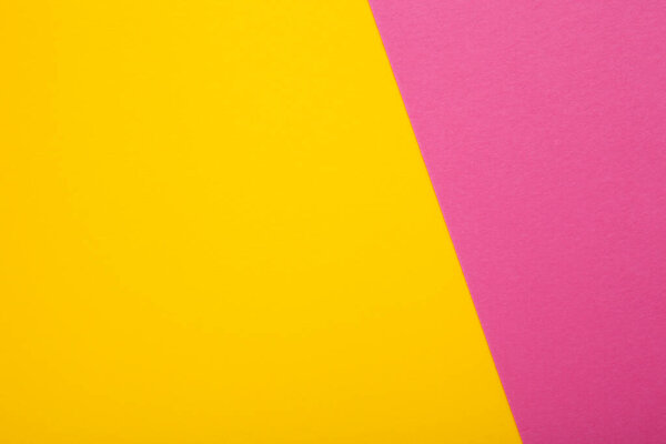 Pink and yellow paper as background. Two colored bright paper texture, top view with place for text