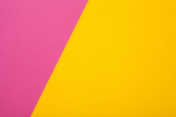 Pink and yellow paper as background. Two colored bright paper texture, top view with place for text