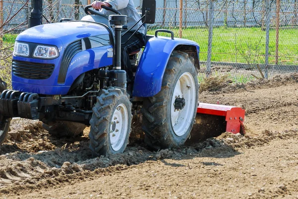 Bauer pflügt das Feld. Kleiner Traktor mit Pflug auf dem Feld. Anbau. — Stockfoto