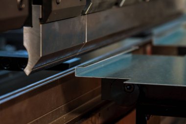 Bending sheet metal with a hydraulic machine at the factory clipart