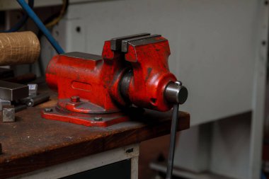Fabrikadaki ahşap masada kırmızı metal mengene.