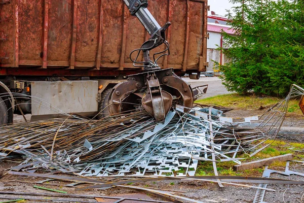 Un camión de garras carga chatarra de metal industrial para el reciclaje. — Foto de Stock