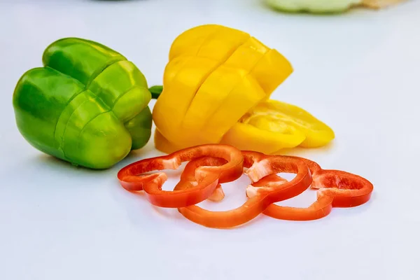 Roter und gelber Paprika in dünne Scheiben auf weißem Hintergrund geschnitten. — Stockfoto