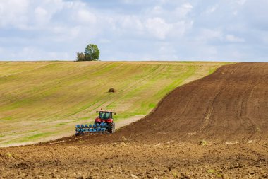 Bir traktördeki çiftçi tohum ekmeden önce toprağı sürer.