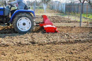 Çiftçi tarlayı sürüyor. Tarlada sabanı olan küçük bir traktör. Topraklama.