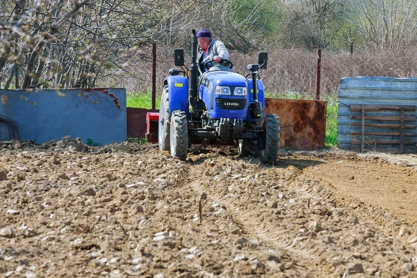 Uzhhorod, Ukrajina, 1. dubna 2019: Farmář orá pole. Malý traktor s pluhem v poli. Pěstování. — Stock fotografie
