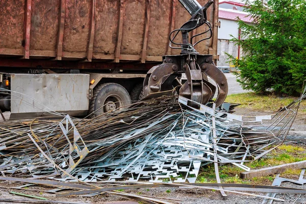 Un camión de garras carga chatarra de metal industrial para el reciclaje. — Foto de Stock