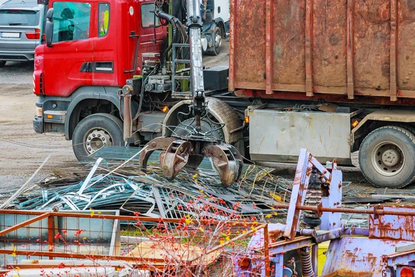 Un camión de garras carga chatarra de metal industrial para el reciclaje. — Foto de Stock
