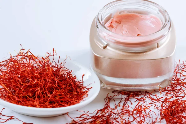 Saffron and cosmetic cream on a white background. Cream with saffron extracts. Stock Picture