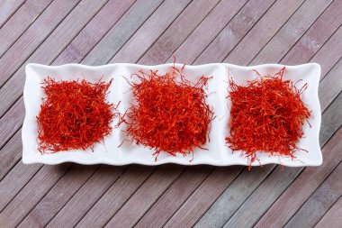 Dry Saffron Spice on a white Plate on Wooden Background. clipart
