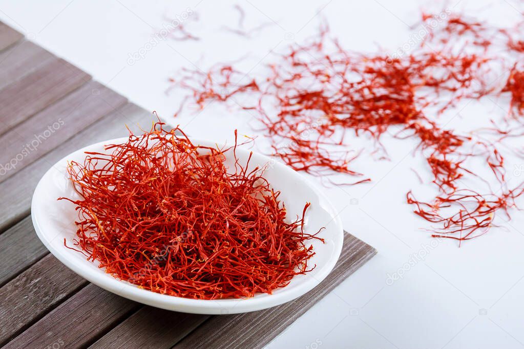 Dry Saffron Spice on a Plate on Wooden Background.