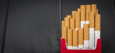 Gri ahşaptan çıkan purolarla dolu açık bir paket sigara.