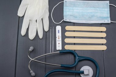 Coronavirus veya covid-19 teşhisi için negatif test, steteskop, eldiven ve gri ahşap arka planda yüz koruma maskesi ile
