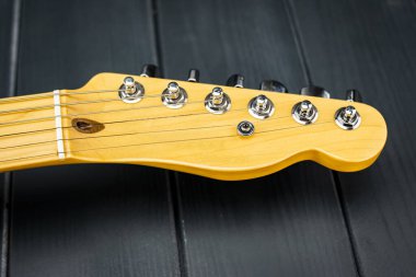 Pırıl pırıl ahşap gitar başlığı, akort tuşları ve krom vidaları var.