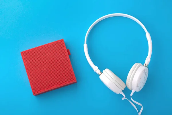 Piros vezeték nélküli hangszóró és fehér vezetékes fejhallgató — Stock Fotó