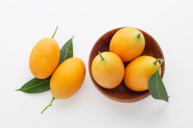 Marian eriği ya da erik mangosu ahşap kasede beyaz arka planda, üst manzara